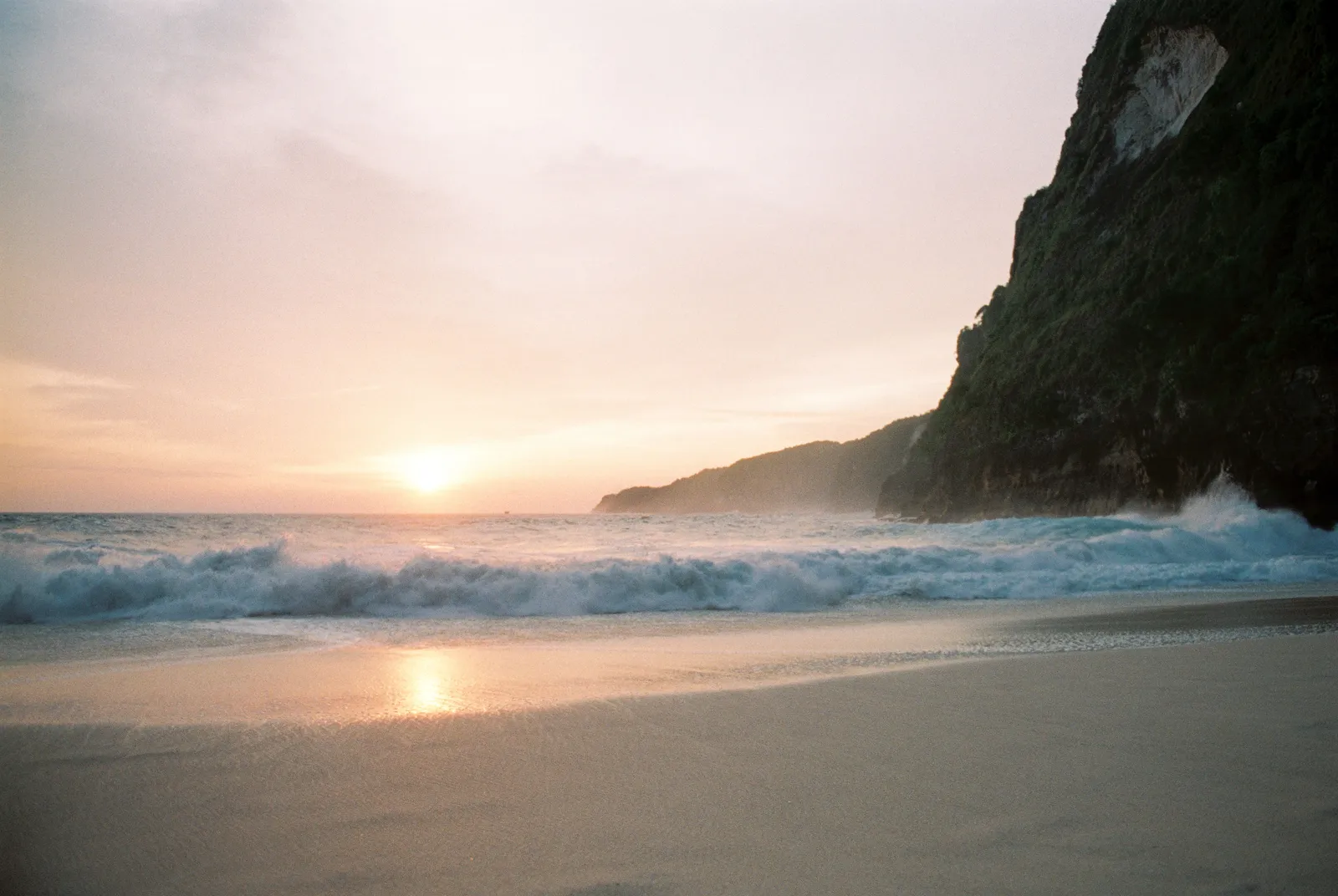 Surf breaking on a beach in southern Bali at sunset