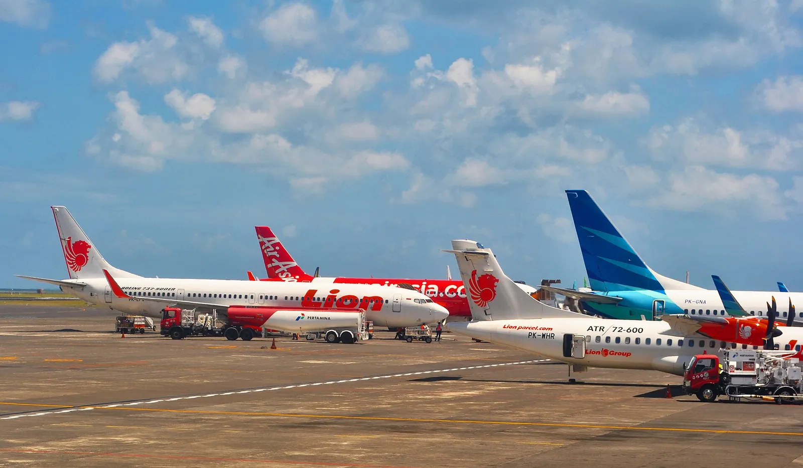 Passenger planes parked on the apron of Ngurah Rai International Airport in Bali under a blue sky