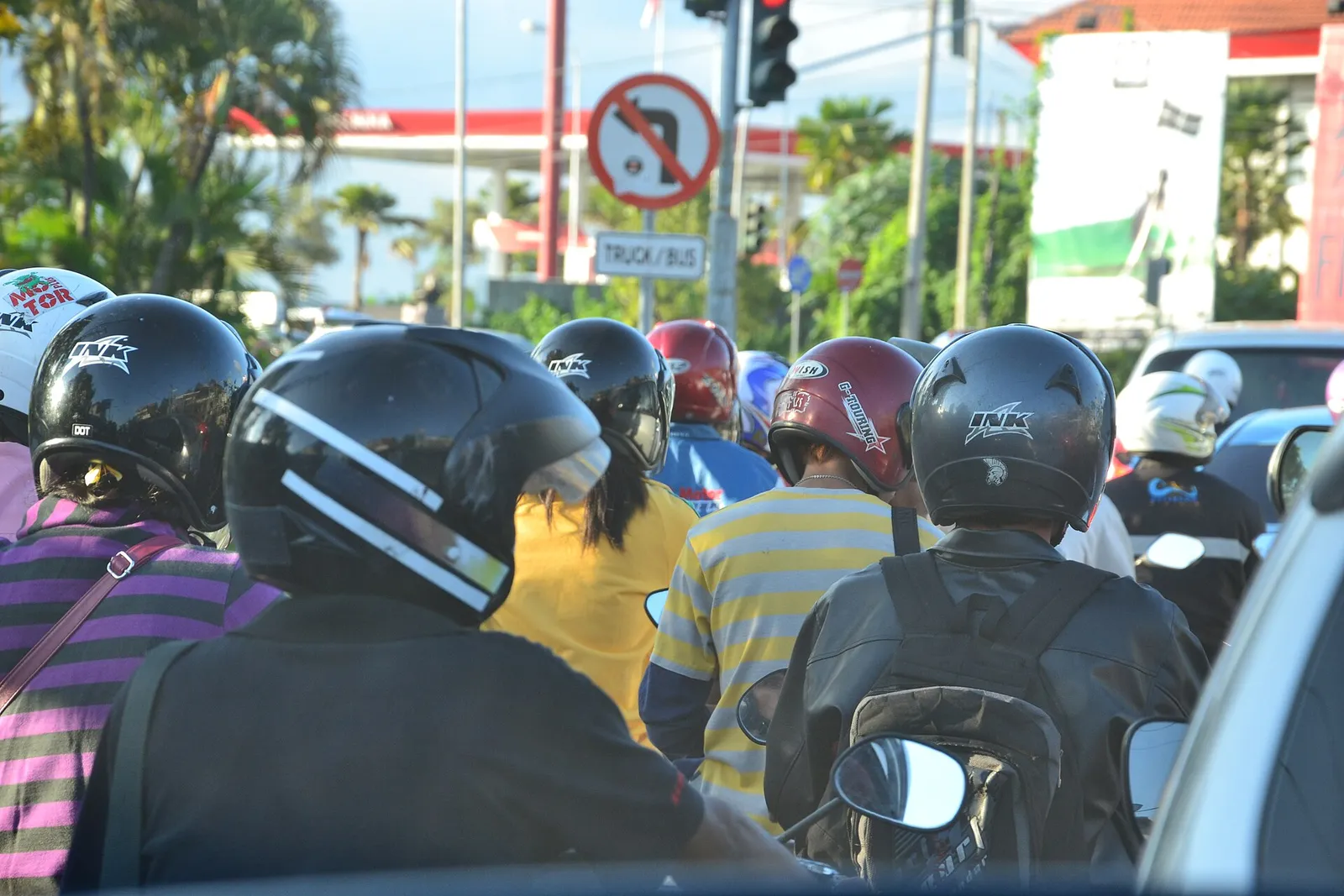 Helmeted motorbike riders queuing in dense traffic at an intersection in Bali