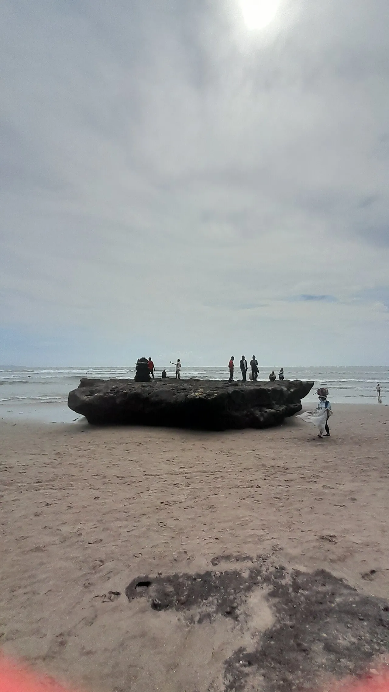 The rock at Batu Bolong beach in Canggu, Bali, with people gathered on it