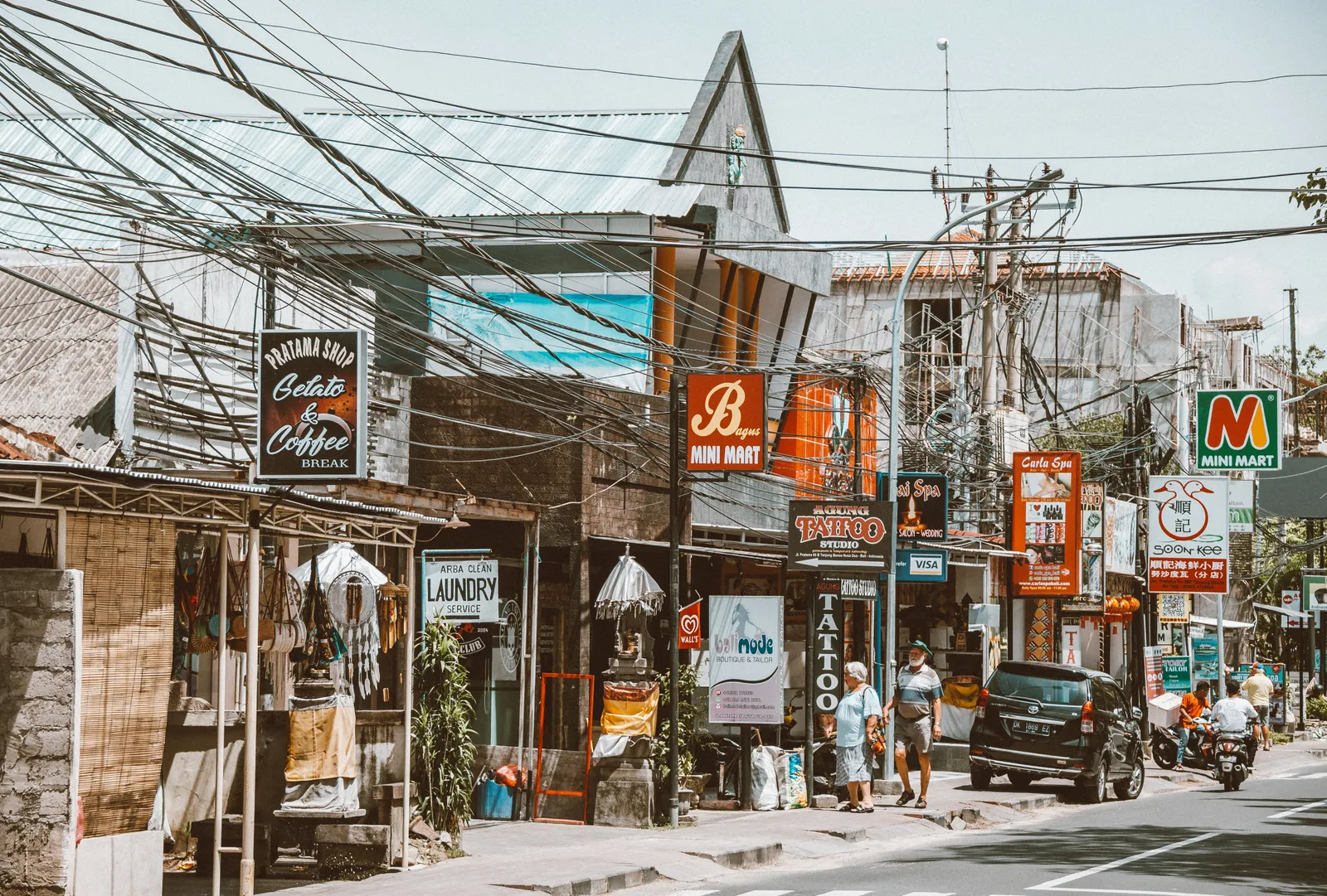 A street lined with bars, laundries and small shops in Bali in daylight