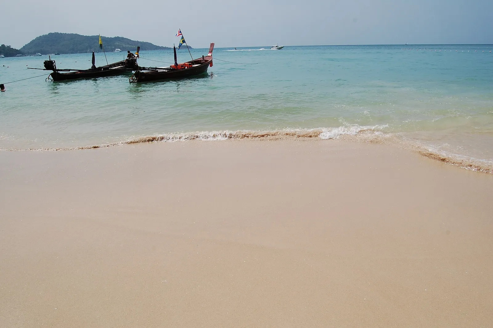 Traditional longtail boats moored in clear turquoise water in southern Thailand