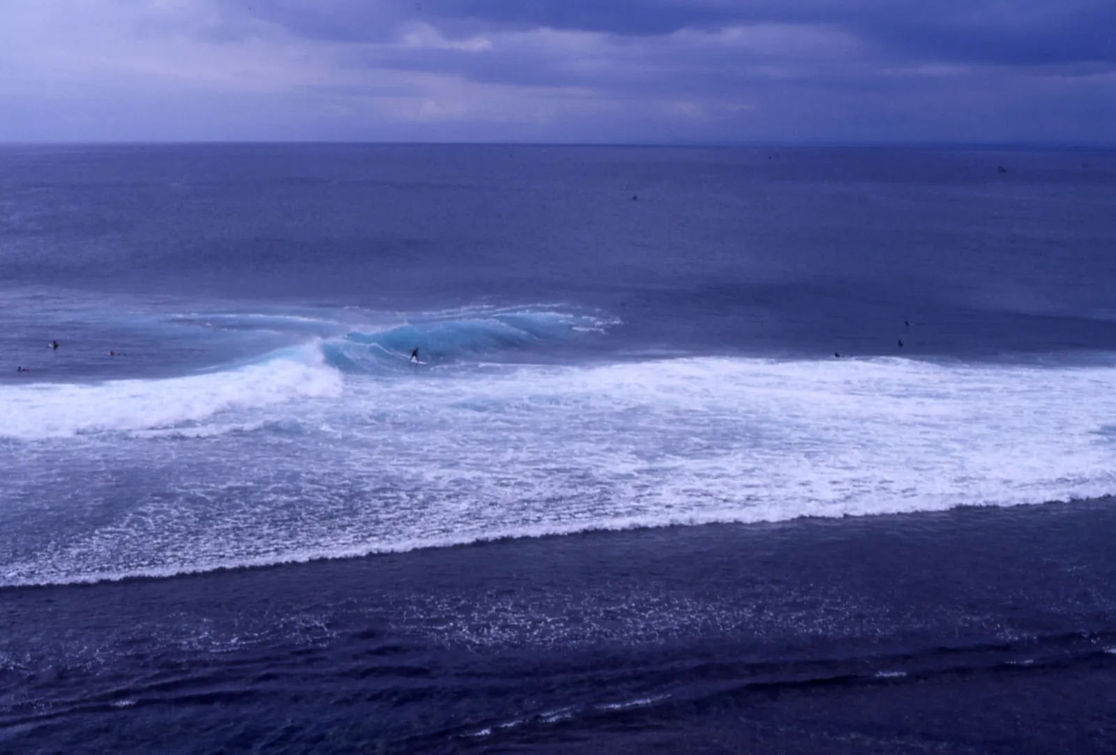 Surfers riding a wave at Uluwatu on Bali's Bukit peninsula