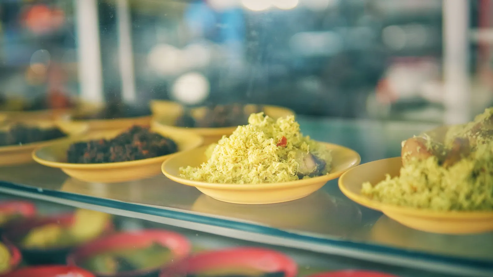 A glass display case of Balinese dishes at a small family-run warung in Bali during the day