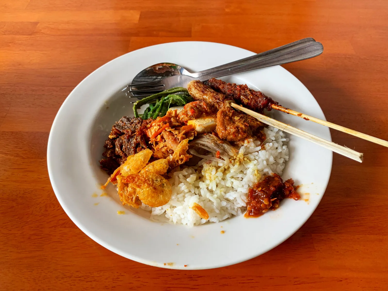 A plate of nasi campur with rice, tempeh, vegetables and sambal at a warung in Bali