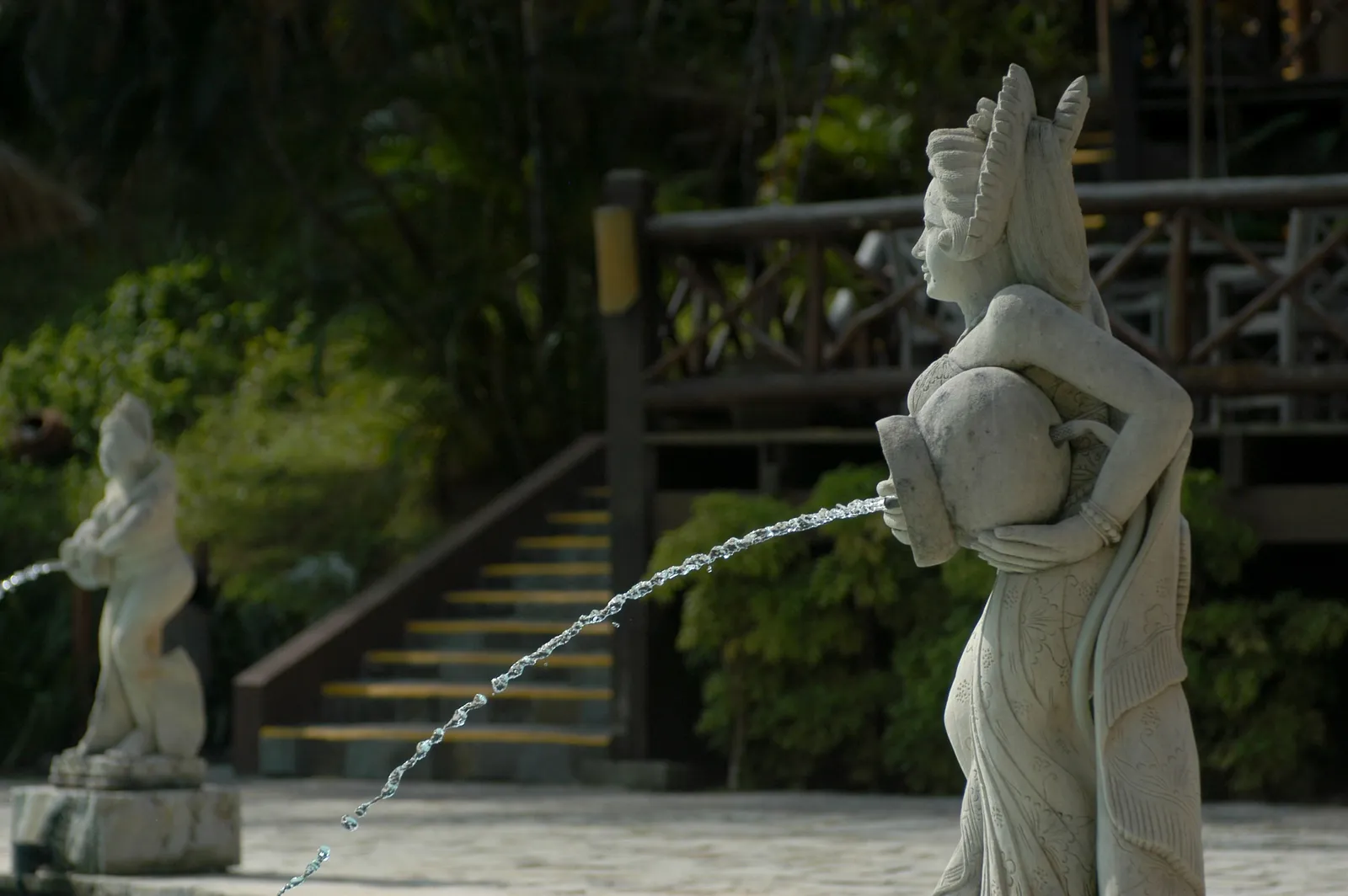 A stone Balinese water feature and tropical garden path at a wellness centre near Ubud