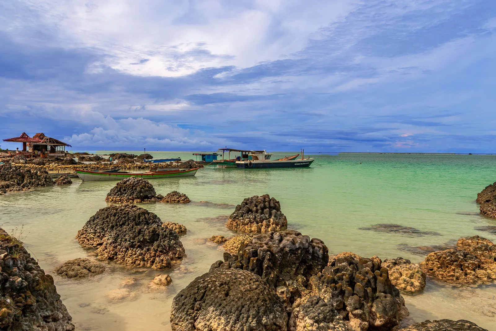 A calm reef-sheltered beach with traditional boats on the east coast of Bali, Indonesia