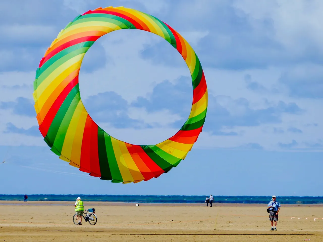 A team launching a large kite on the black sand at Padang Galak beach near Sanur, Bali