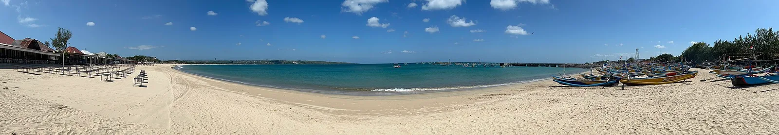 The curved sandy bay and calm water at Jimbaran in Bali, Indonesia