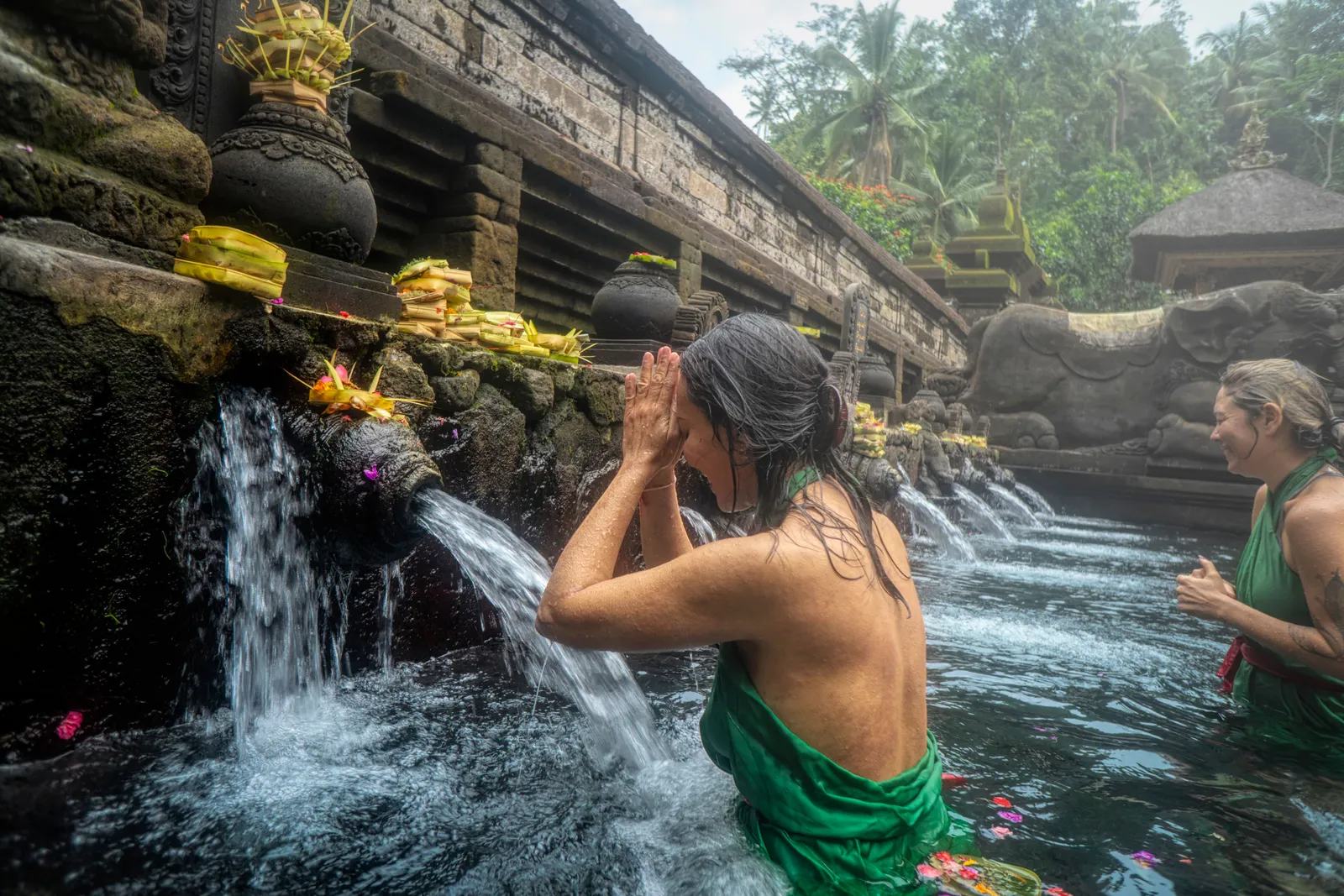 A woman standing in front of flowing water at a purification pool in Bali