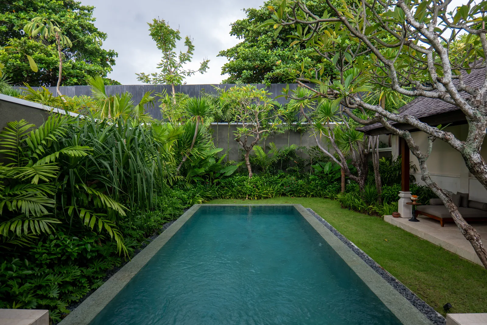 a quiet villa garden in Bali with a private pool and tropical planting, empty in daylight