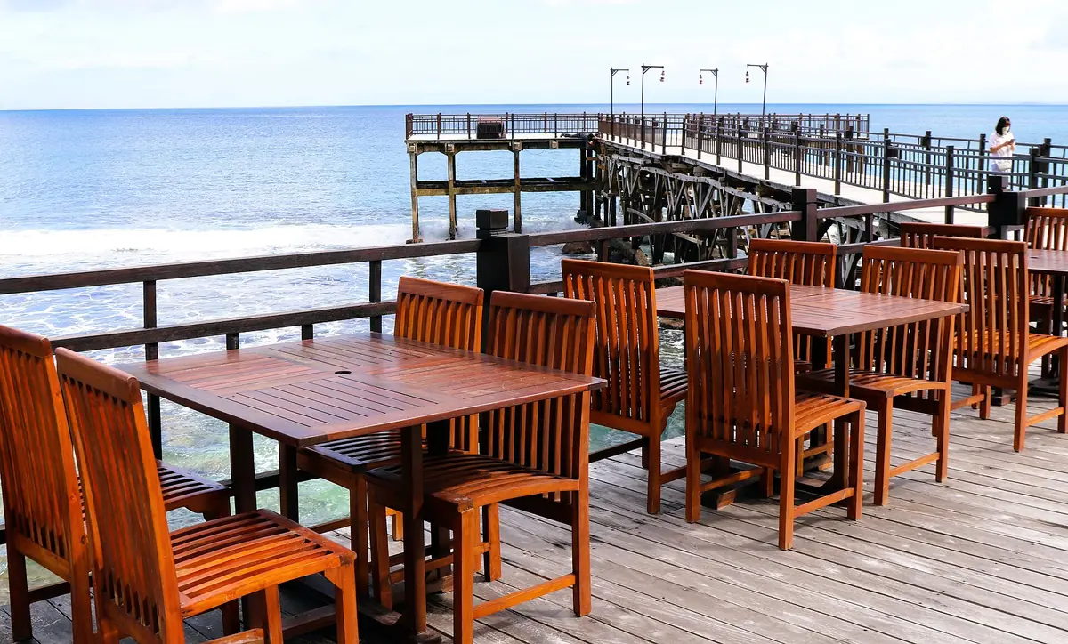 Wooden tables on a deck above the sea