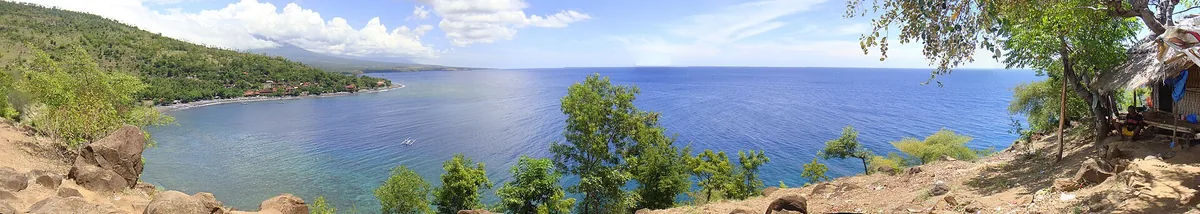A bay of blue water with trees on the slope