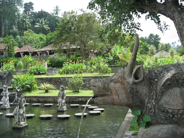 A water pool with round stepping stones and stone statues, a carved animal head spouting a jet of water
