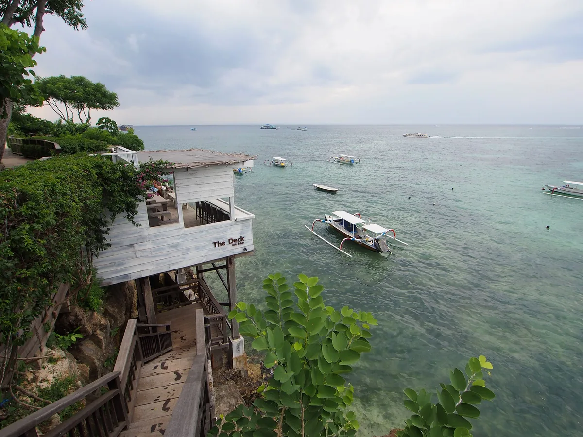 A wooden deck above shallow water with boats