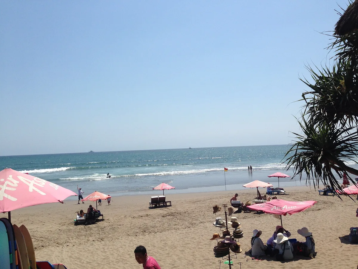 A beach with pink parasols and sun loungers