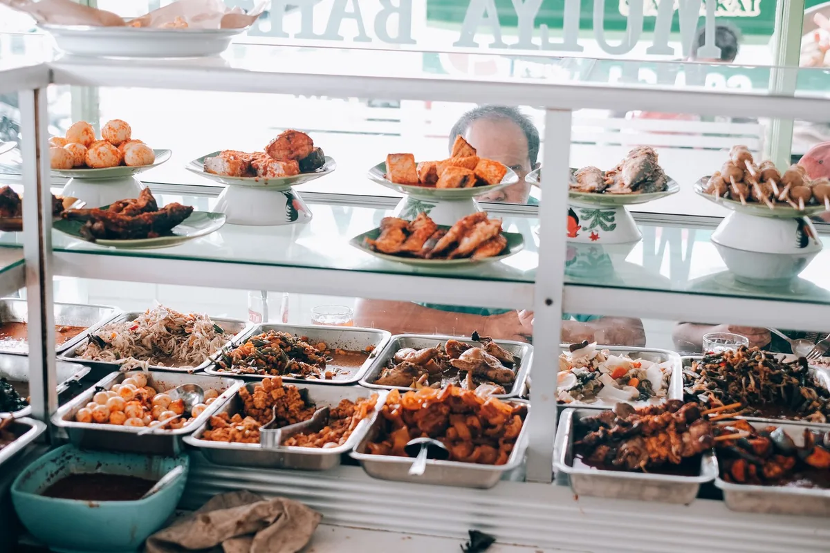 Trays of fried dishes in a warung display case