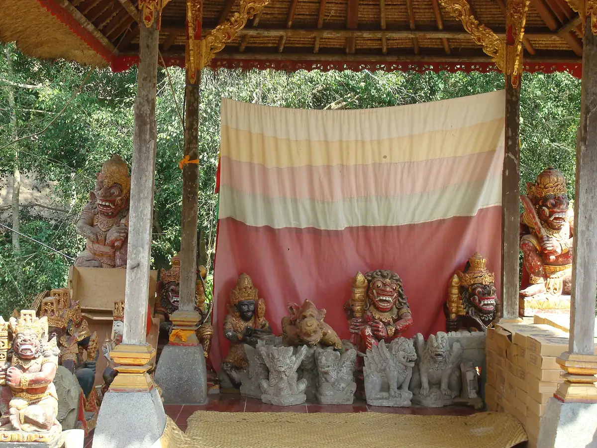 A covered Hindu shrine with a red and white cloth drape and stone guardian statues on either side