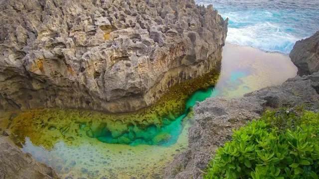 A natural pool of turquoise water enclosed in a limestone shelf at the ocean edge