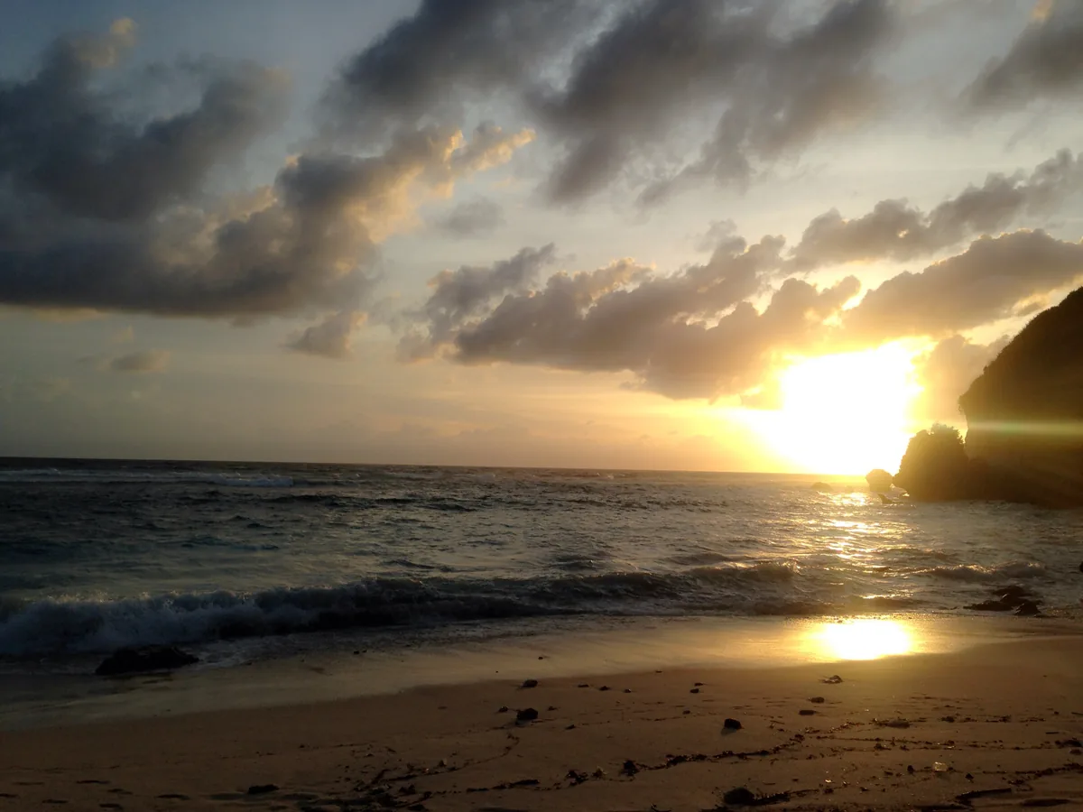 Sunset over the sea from the edge of a cliff
