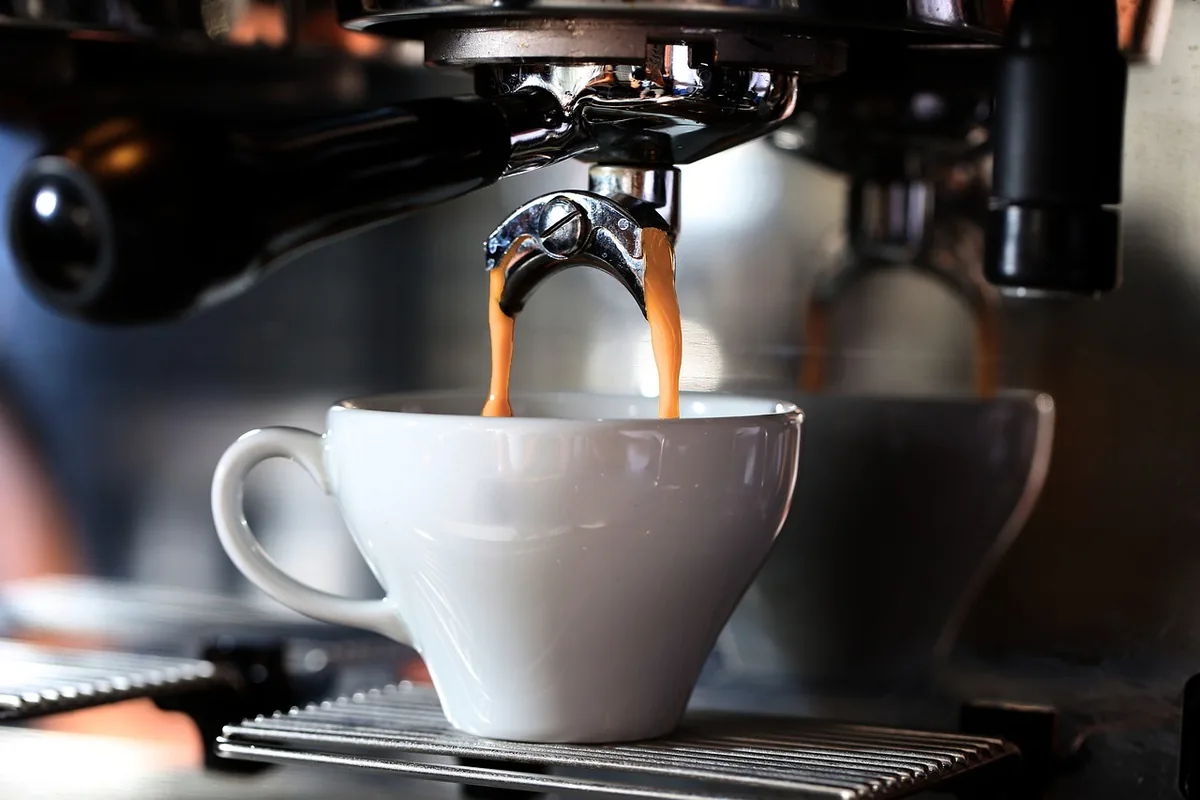 Espresso pouring from a machine into a white cup