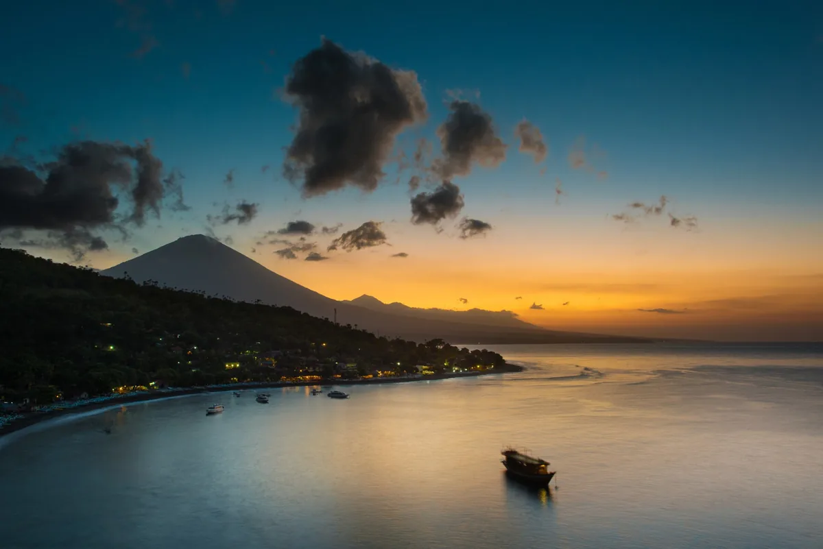 A bay at dusk with a boat and a mountain ridge