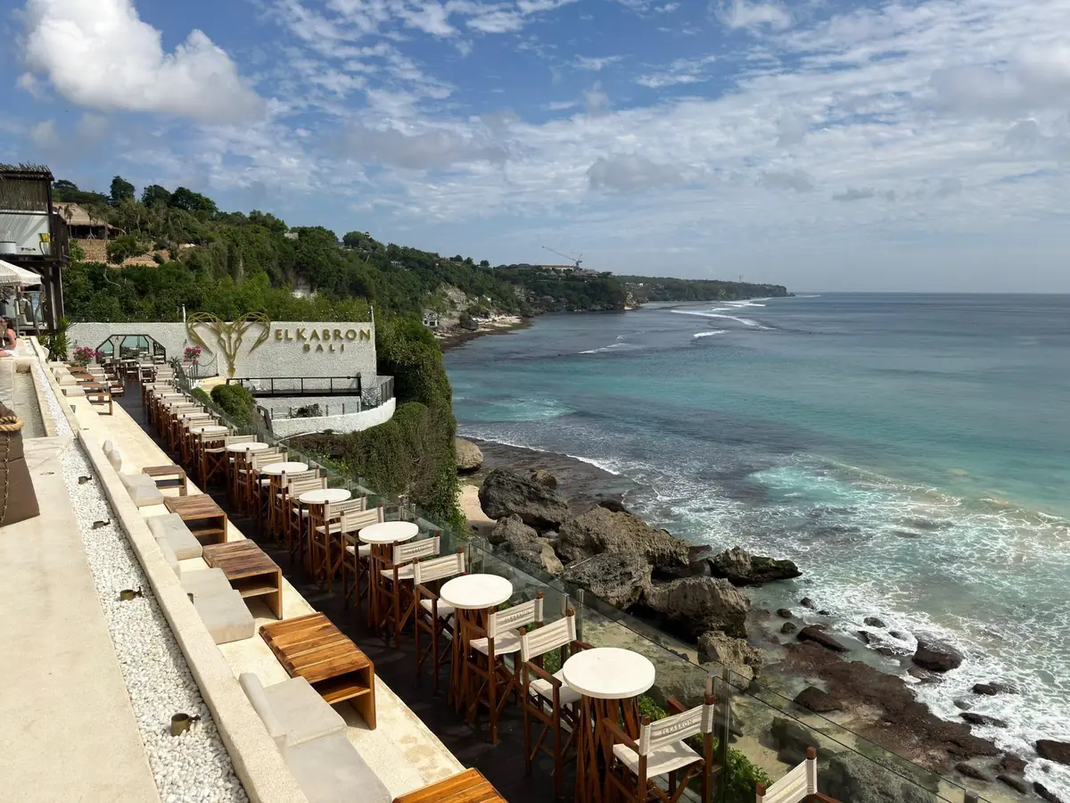 A terrace of sun loungers above a rocky shoreline