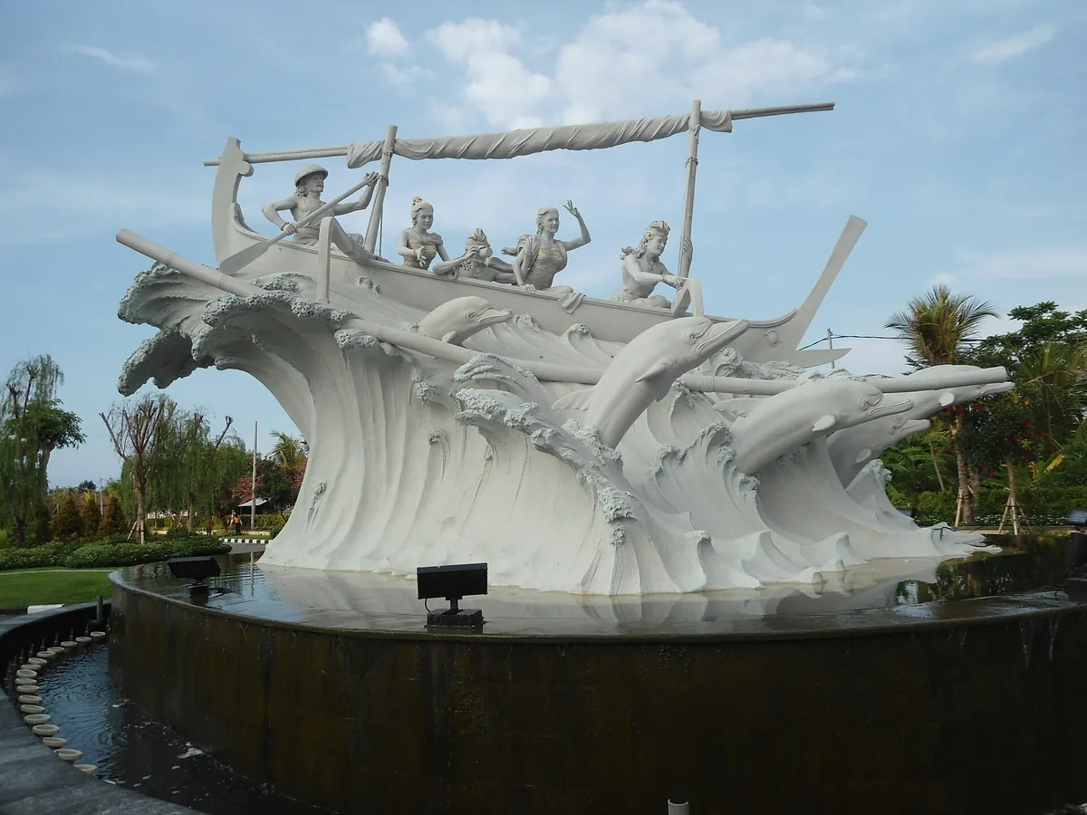 A white dolphin monument on a stone plinth, ringed by palms under a bright sky