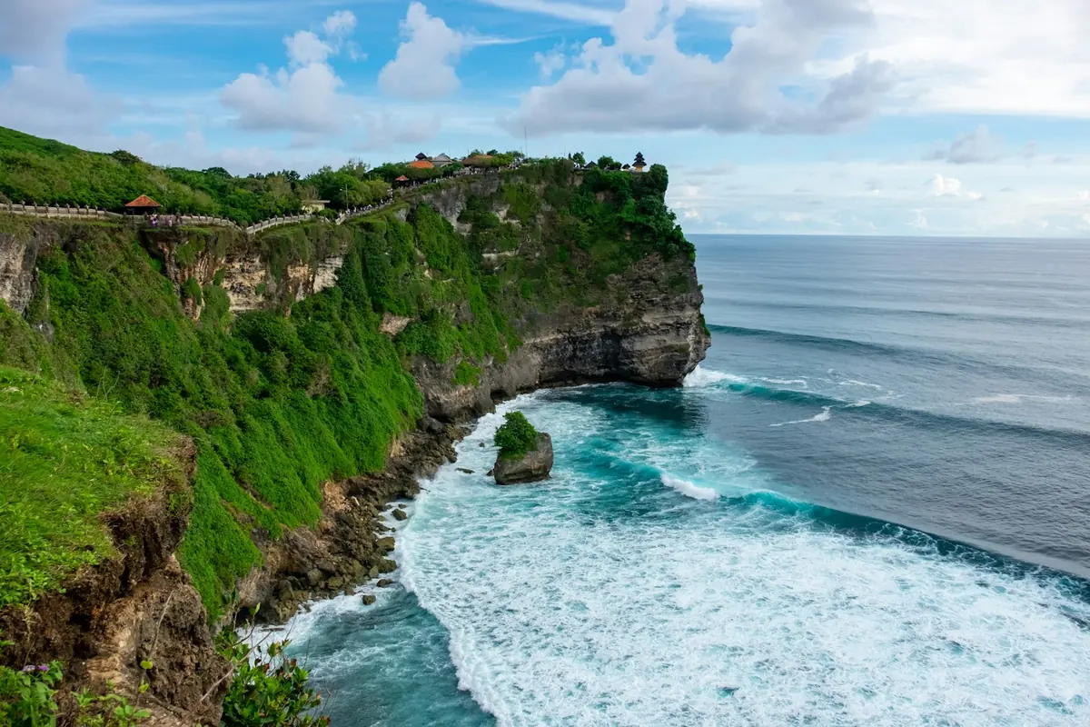 A green clifftop path above breaking waves