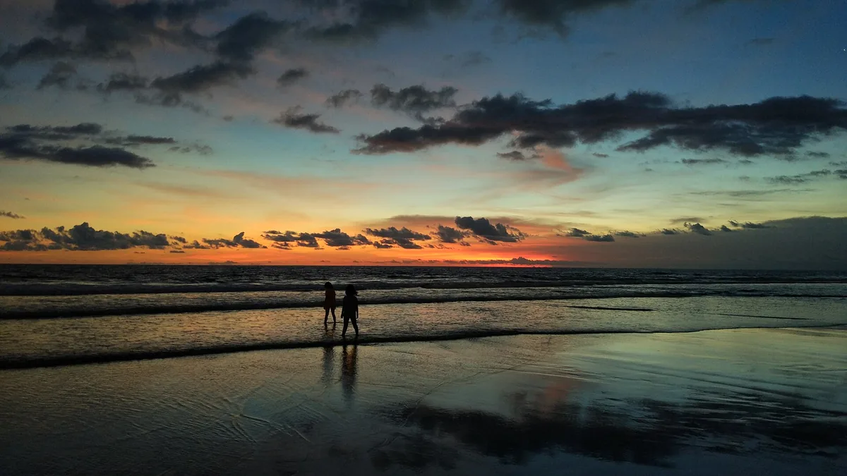 A beach at sunset with figures in silhouette