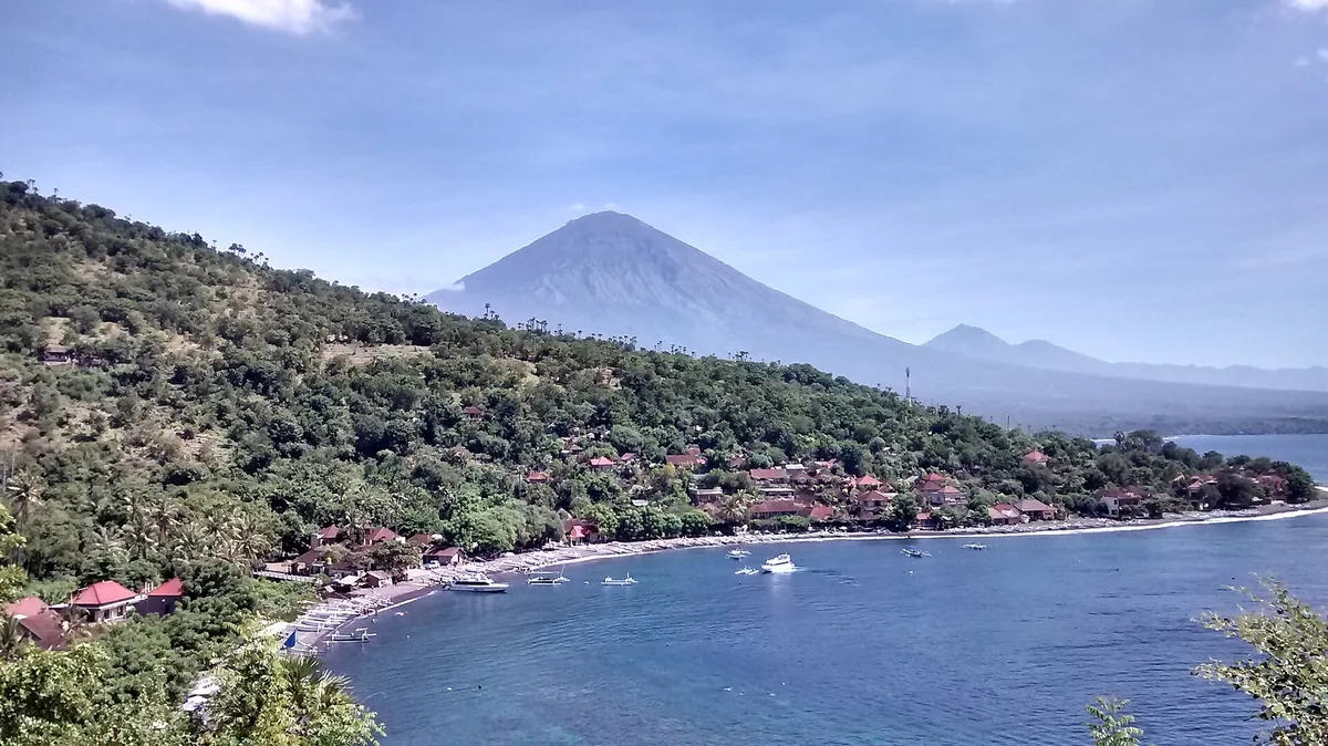 A bay with boats and a volcano silhouette behind