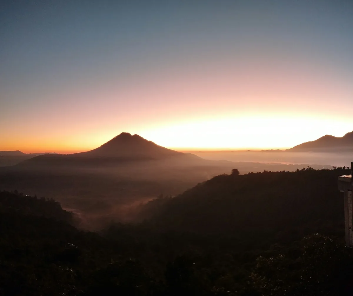 Sunrise over a volcano summit with mist in the valley