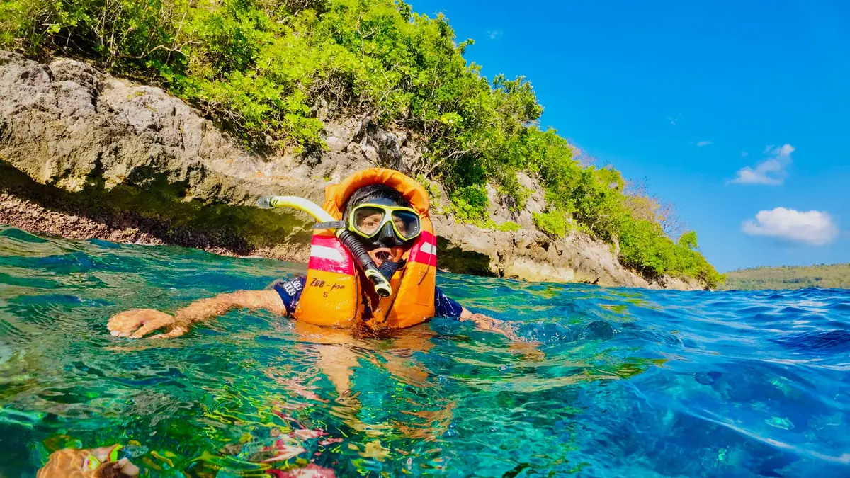 A snorkeller in clear water at the surface above a reef