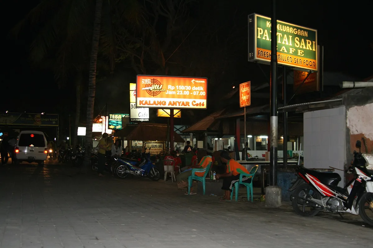 A street of lit seafood warungs at dusk