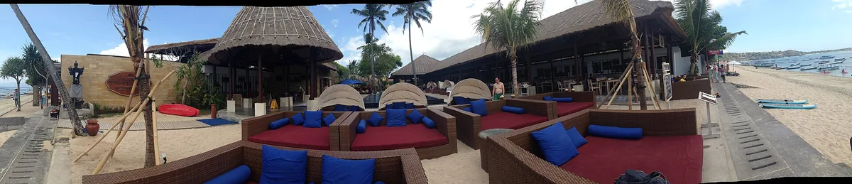 Blue daybeds under thatched roofs facing the sea