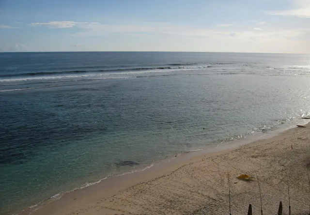 A view from above of a long empty strip of sand, a reef and open sea to the horizon