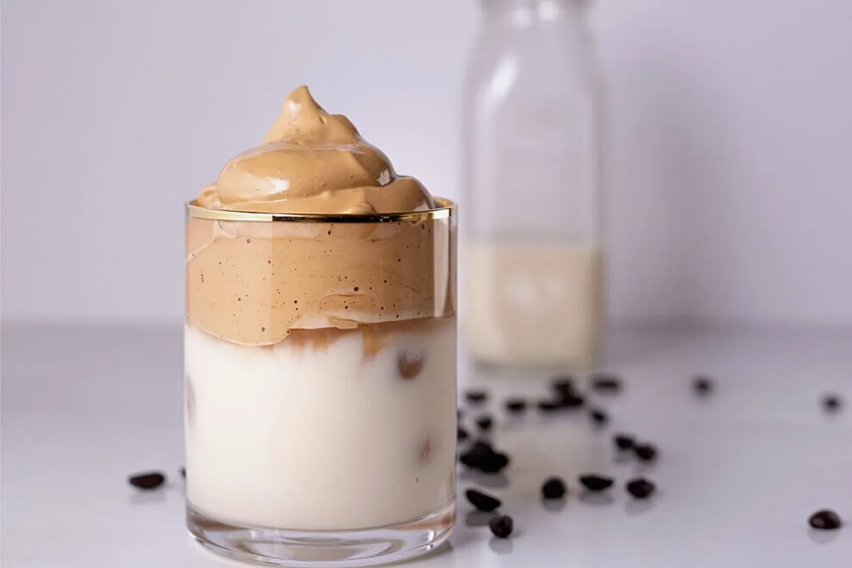 A dalgona coffee in a glass beside a bottle of milk