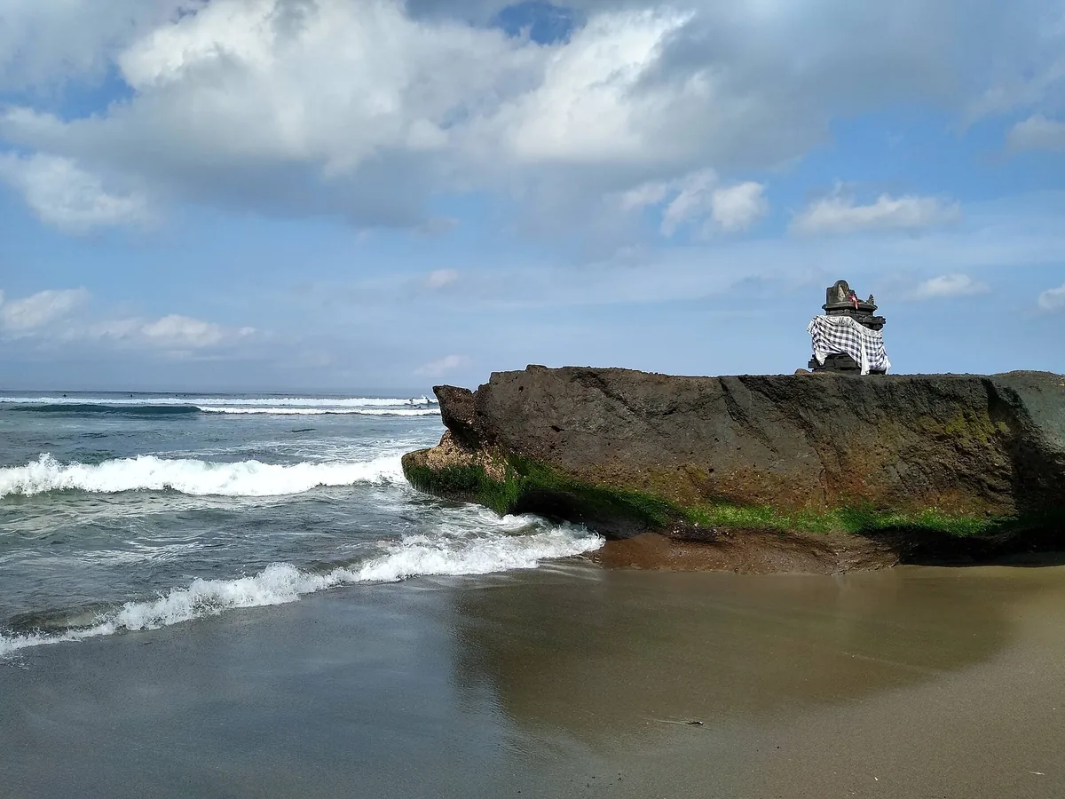 A rock with a small shrine at the edge of the beach