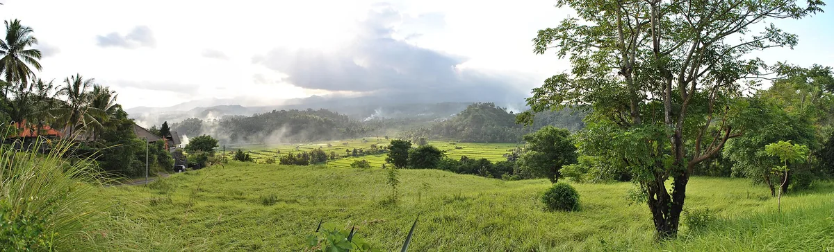 Green fields and a mountain ridge in morning mist