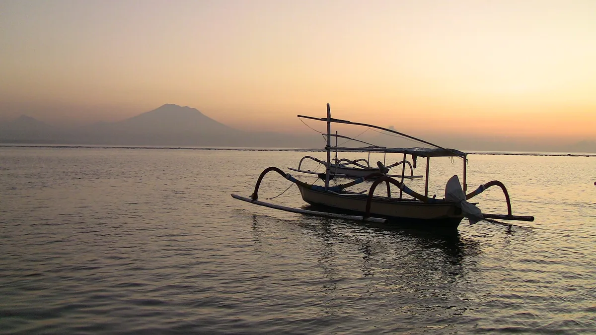 A traditional outrigger before a mountain at sunrise