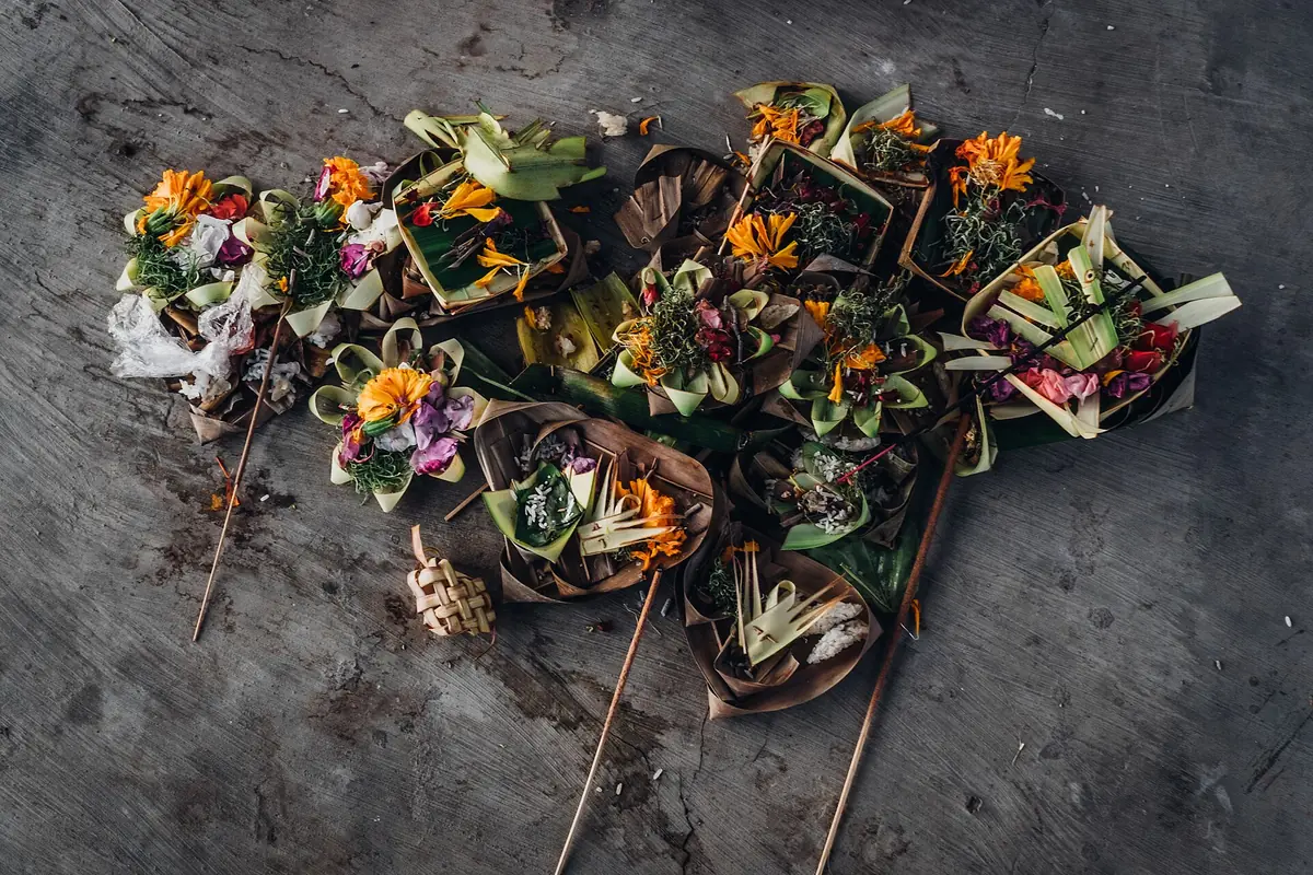 Flower offerings in woven leaf baskets on stone