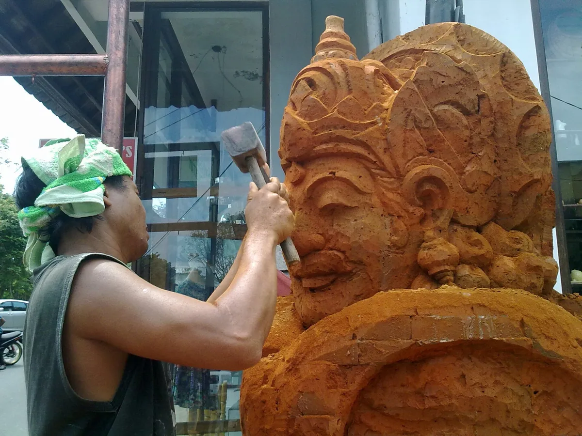 A carver working a wooden sculpture in a workshop