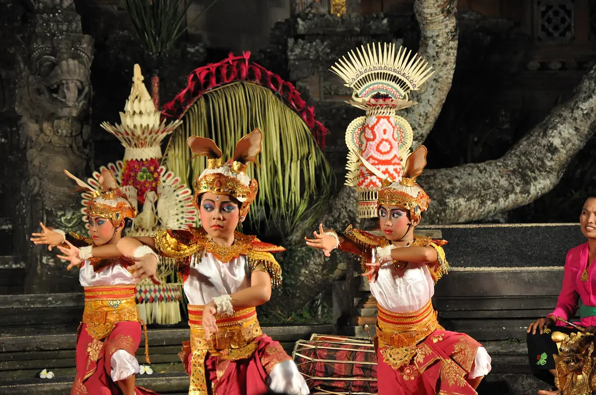 Balinese dancers in traditional costume before a carved temple wall