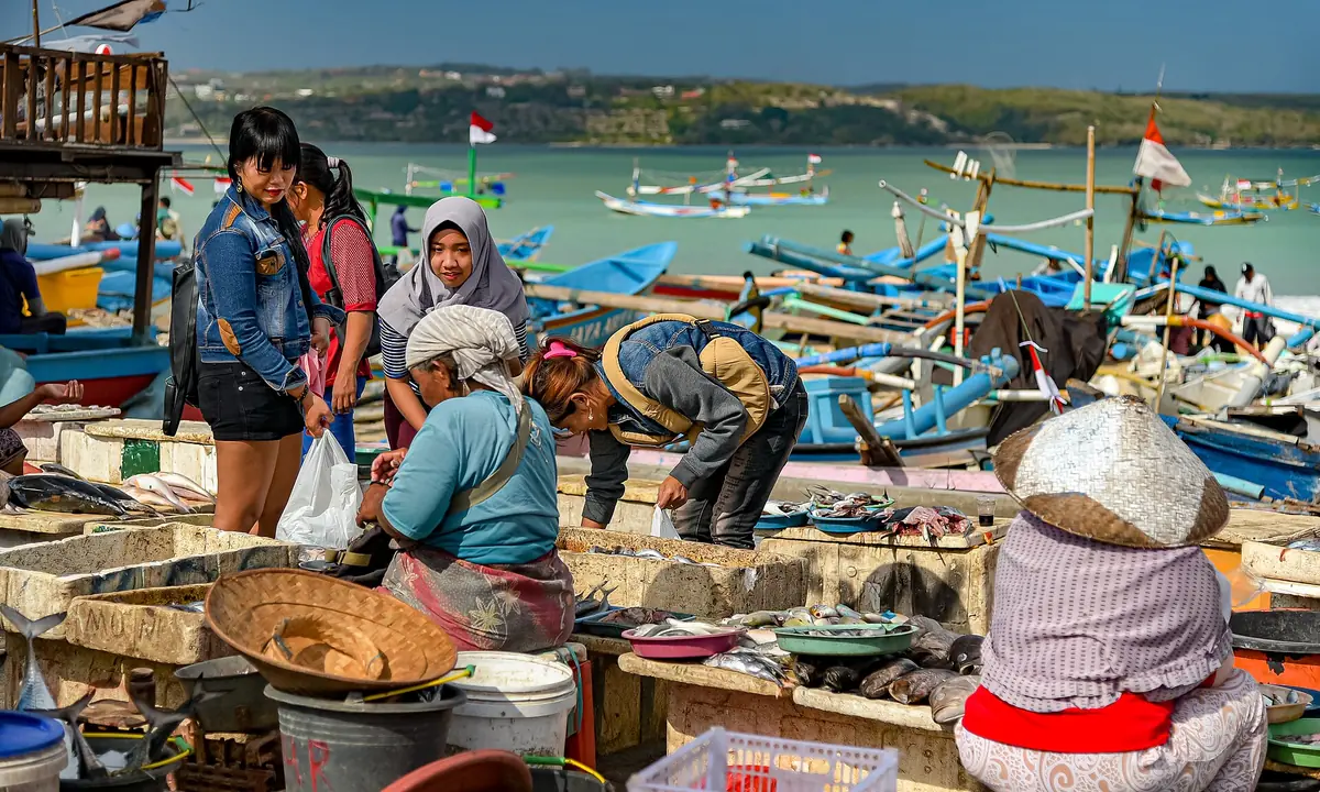 A fish market on the sand with boats behind