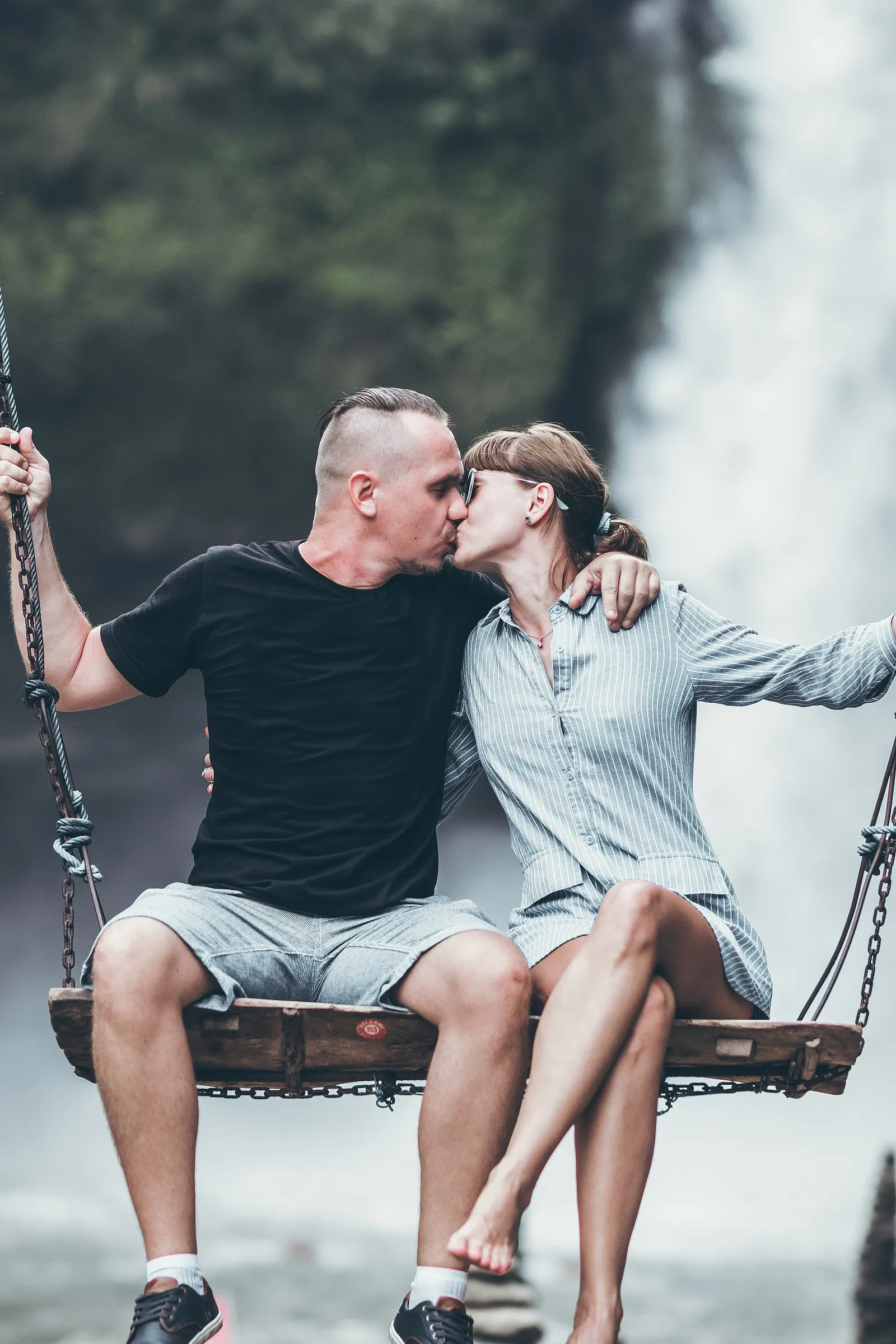 A couple on a jungle swing in front of a waterfall near Ubud, Bali